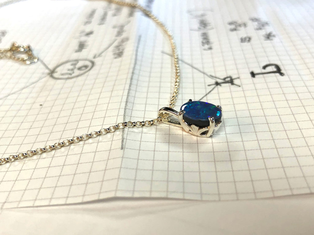 opal necklace on top of design drawings