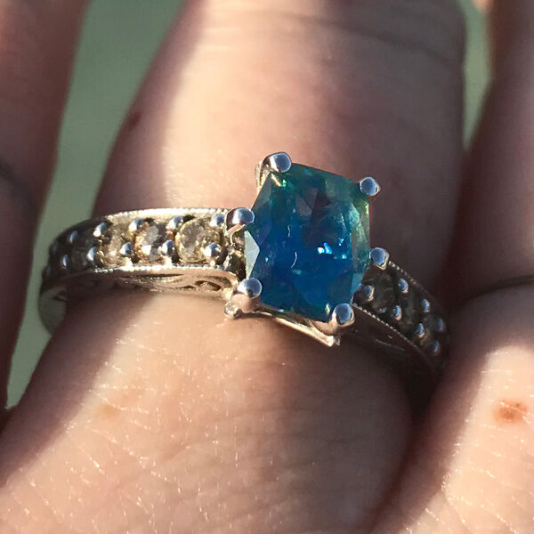 teal sapphire and diamond engagement ring (on finger)