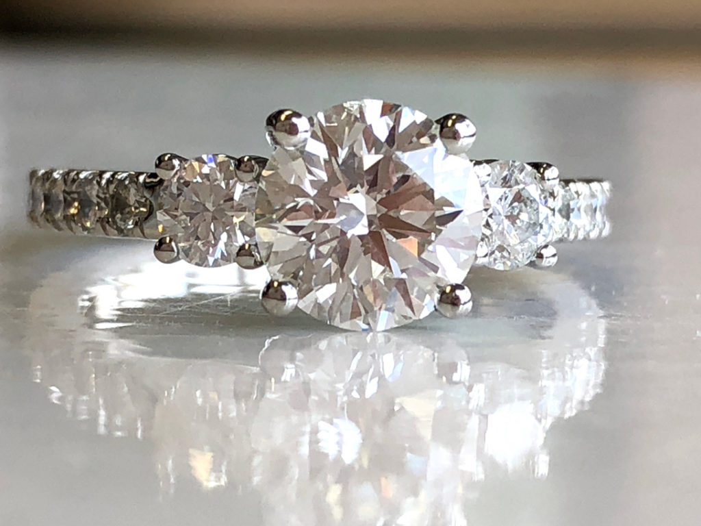 stunning ring has large center diamond, medium side diamonds, several french-set diamonds